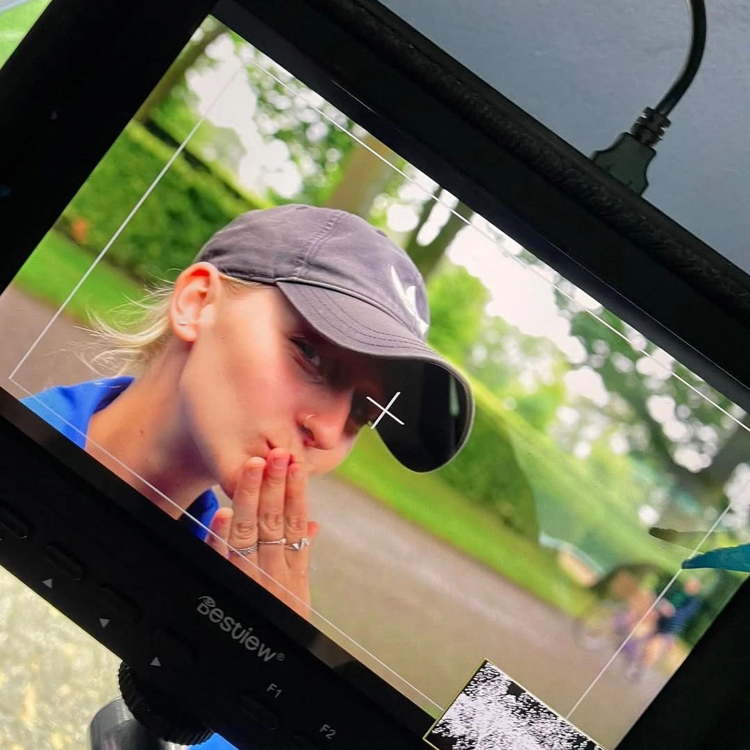 Ylke blaast een kus, gezien door het afkijkscherm van de camera op een filmset.